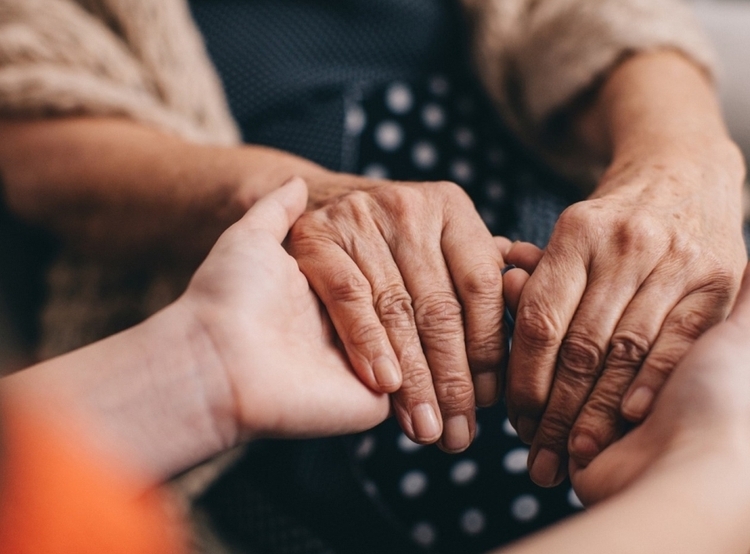 senior and youth holding hands